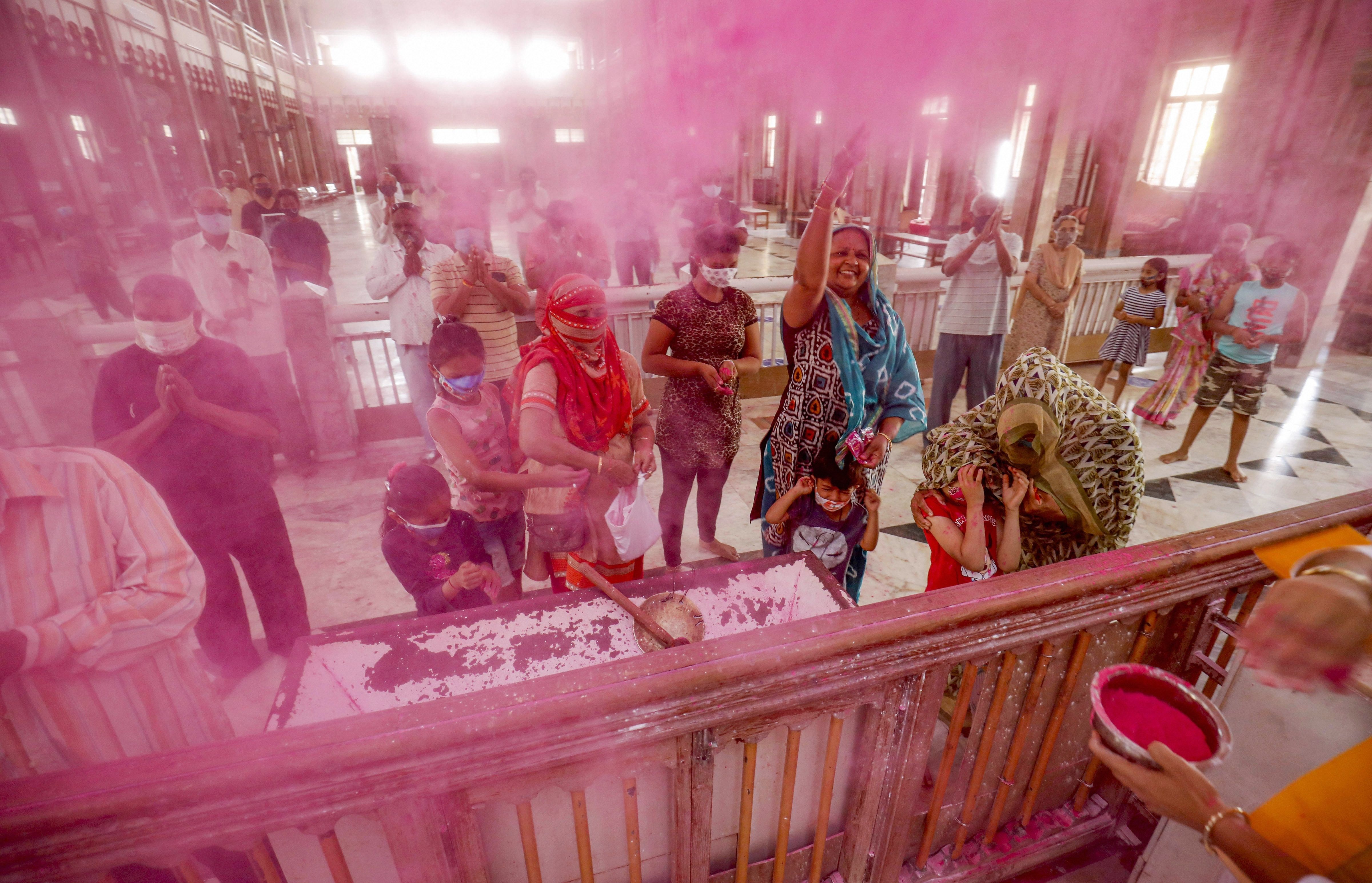 Holi 2021: Priests throw colour powder on devotees, ahead of Holi festival, inside the Lord Krishna temple in Ahmedabad.