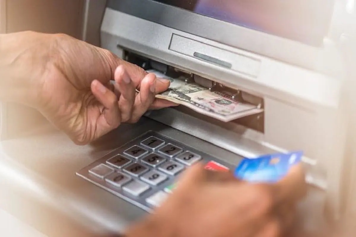  A person inserts a credit card into an ATM machine to withdraw cash.