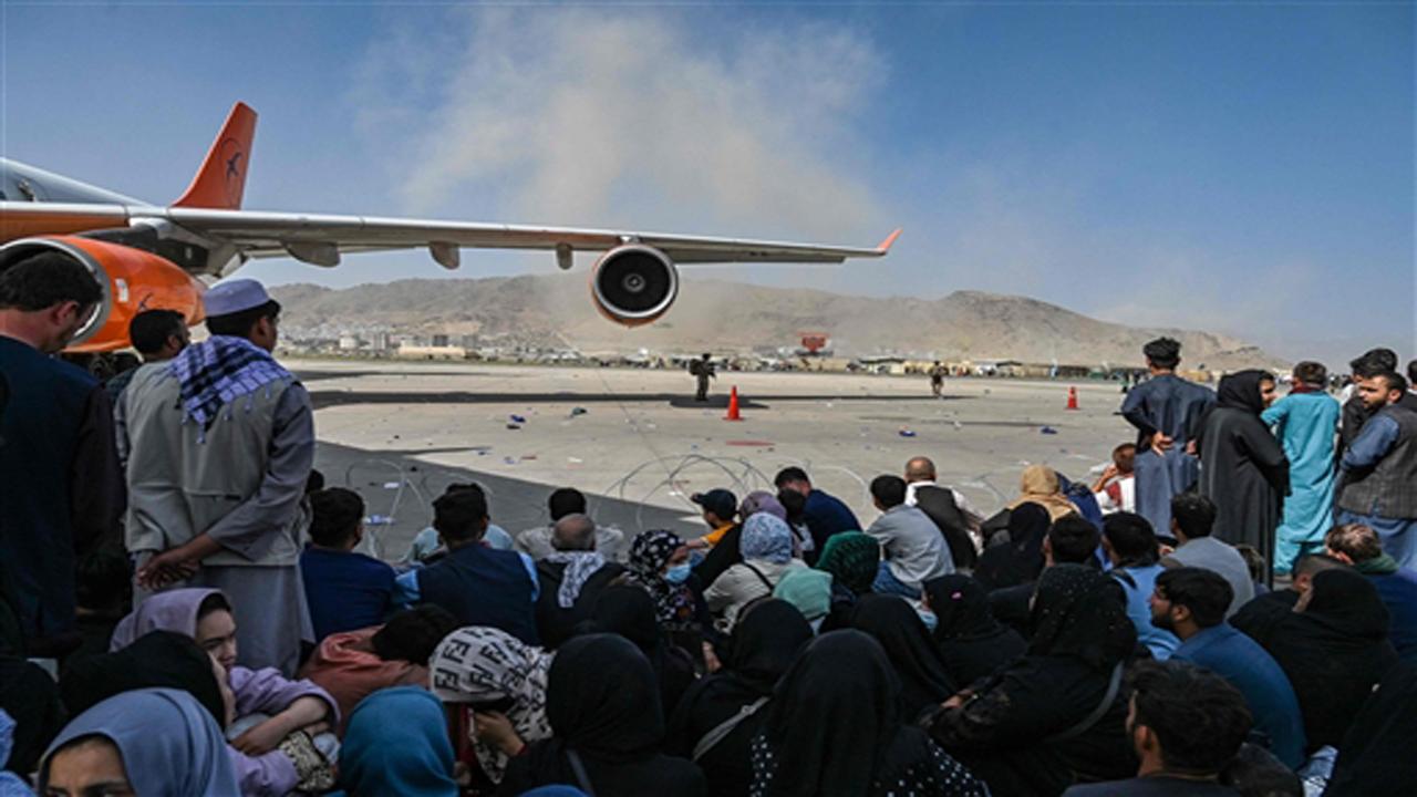 Afghan people sit as they wait to leave the Kabul airport. Pic/AFP