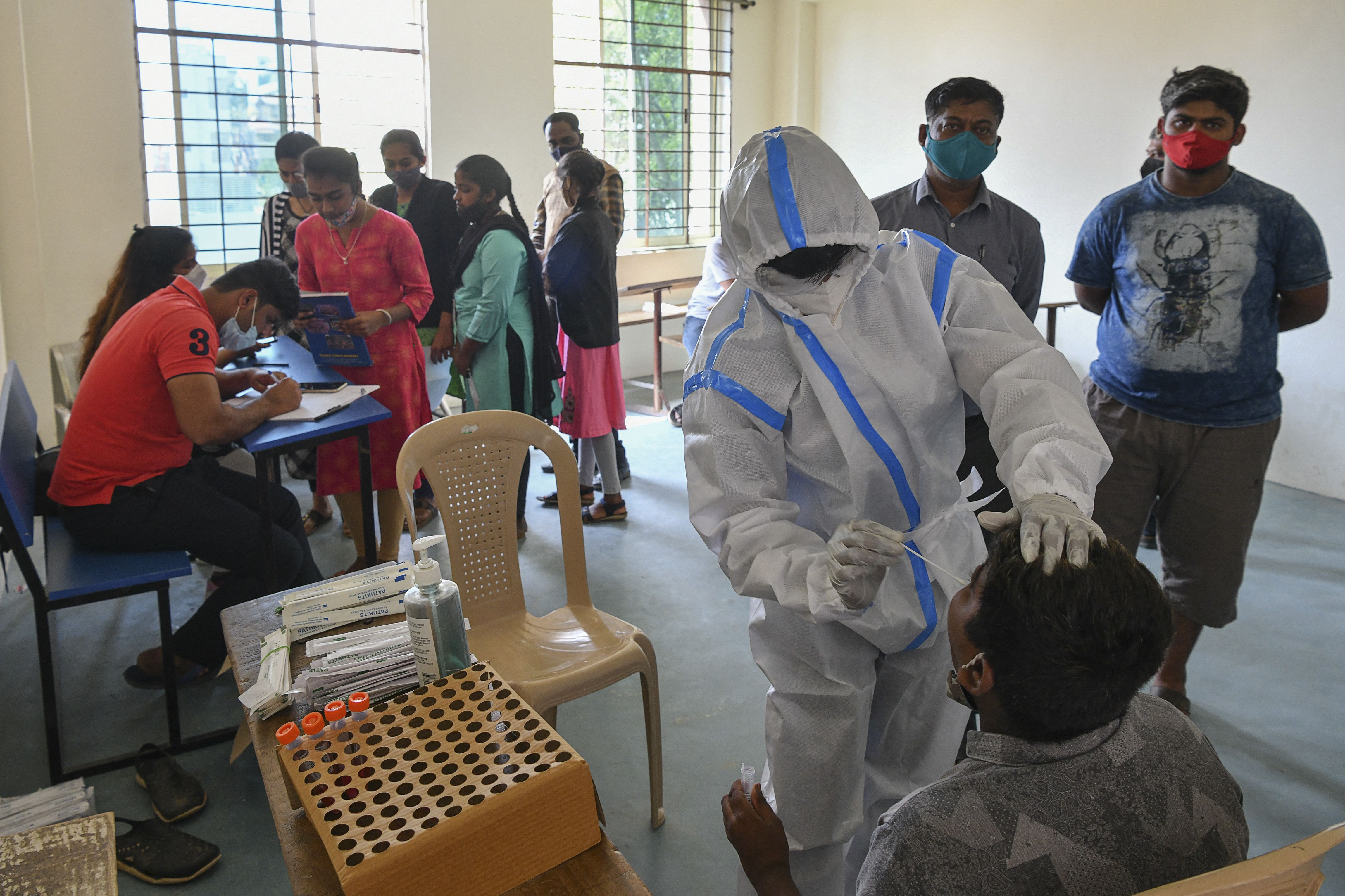 A medical worker takes a swab sample from a man for a reverse transcription polymerase chain reaction (RT-PCR) test for the Covid-19 coronavirus at a college in Bangalore on January 19, 2022.