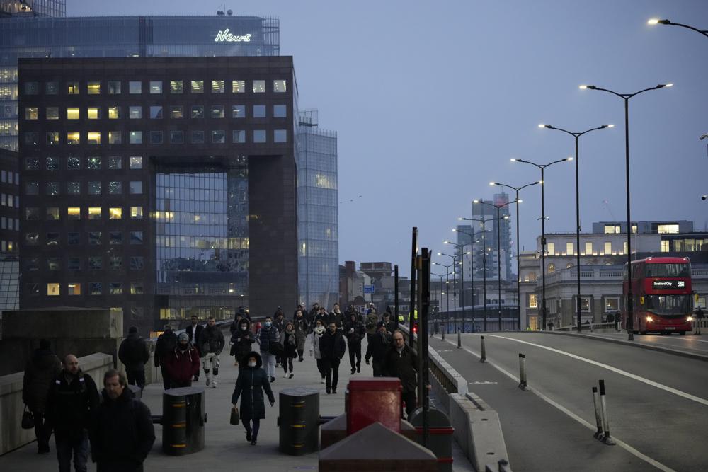 Workers walk over London Bridge towards the City of London financial district during the morning commute, in London, Monday, Jan. 24, 2022. The British government have asked people to return to working in offices starting Monday as they ease coronavirus restrictions. (AP Photo/Matt Dunham)