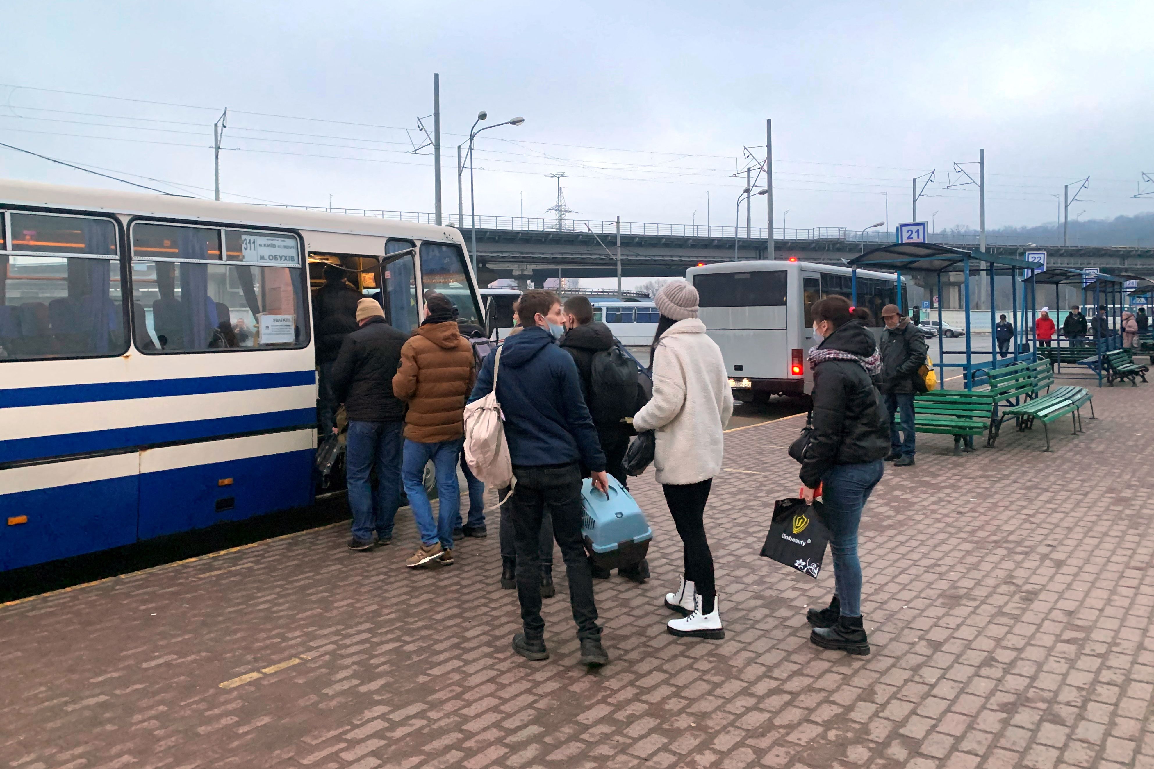 People board a bus at the Vydubytchi bus station in Kyiv in the morning of February 24, 2022. Russian President Vladimir Putin announced a military operation in Ukraine on Thursday with explosions heard soon after across the country and its foreign minister warning a 
