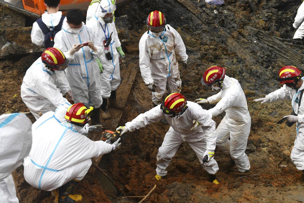 In this photo released by Xinhua News Agency, rescuers identify objects collected at the core site of Monday's plane crash in Tengxian County, southern China's Guangxi Zhuang Autonomous Region, Friday, March 25, 2022. Construction excavators dug into the crash site Saturday in the search for wreckage, remains and the second black box from a China Eastern 737-800 that nosedived into a mountainside in southern China this week with 132 people on board. (Lu Boan/Xinhua via AP)