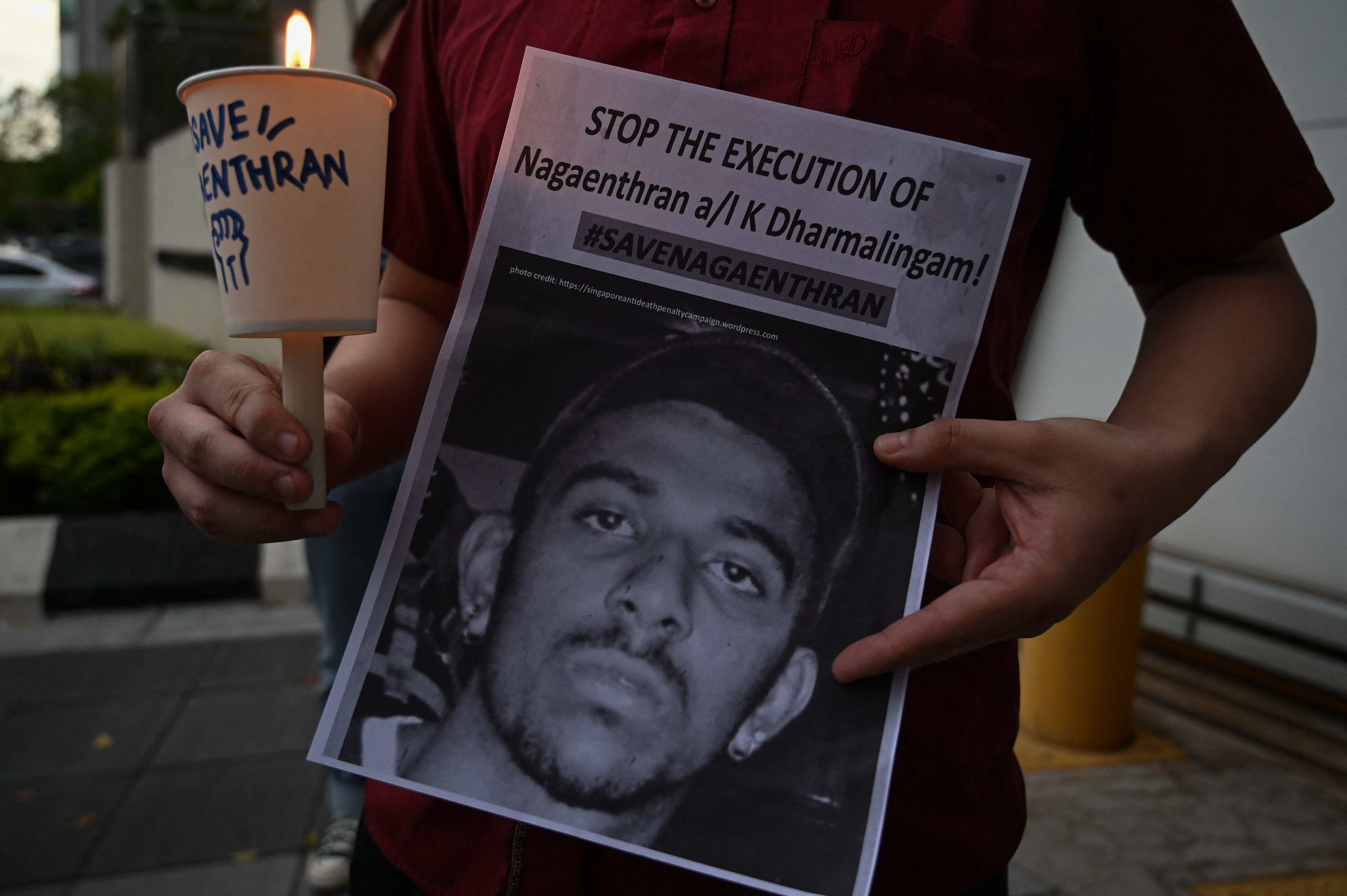 An activist holding a placard attends a candlelight vigil against the impending execution of Nagaenthran K. Dharmalingam, sentenced to death for trafficking heroin into Singapore, outside the Singaporean embassy in Kuala Lumpur on November 8, 2021. (AFP Photo)