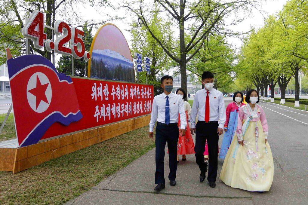 Women dressed in traditional Korean attire walk past a celebrative poster on the 90th founding anniversary of the Korean People's Revolutionary Army in Pyongyang, North Korea, Monday, April 25, 2022. The poster reads