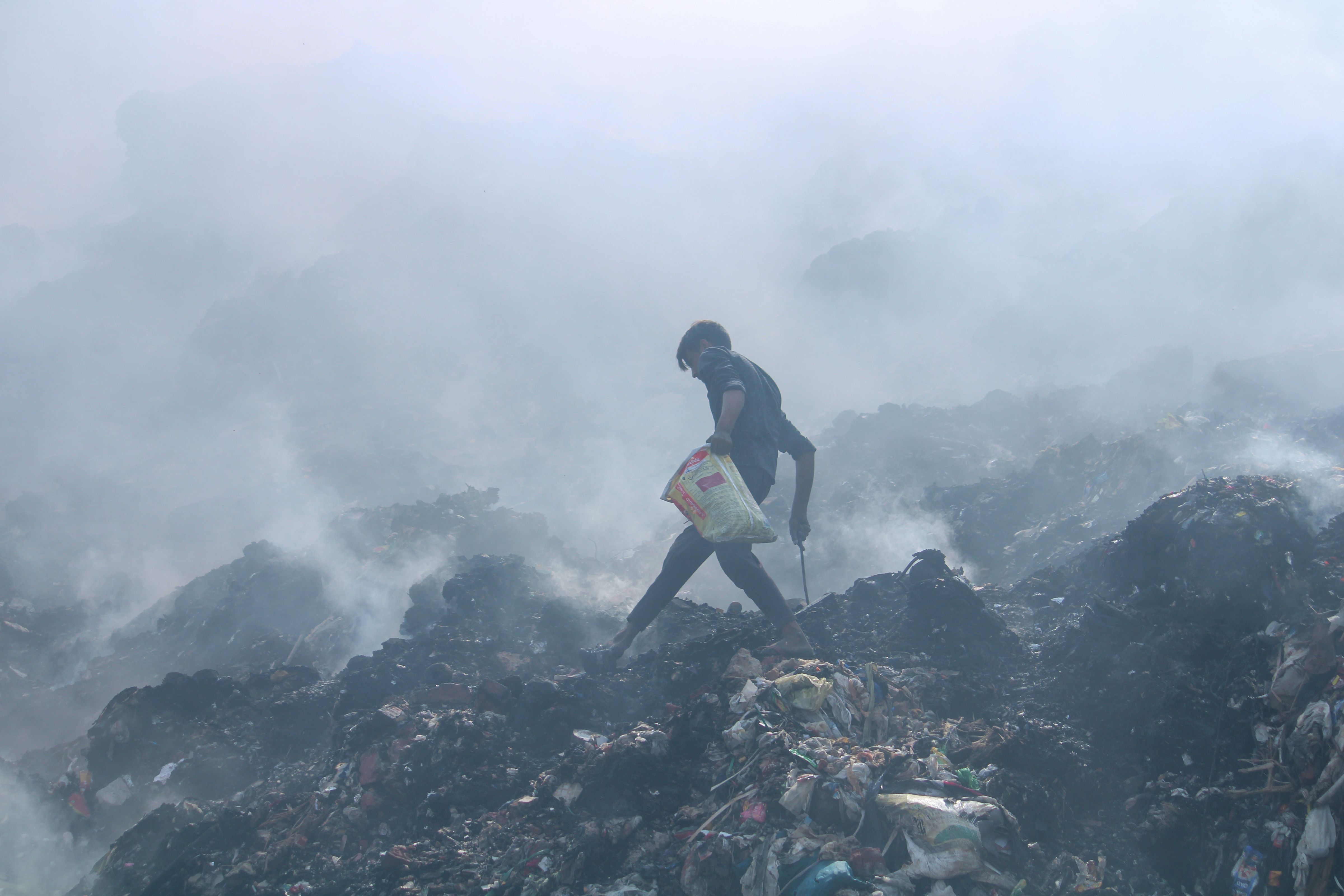 A local at the site, as smoke rises from a fire that broke out at Bhalswa landfill, in New Delhi, Wednesday, April 27, 2022. (PTI Photo)
