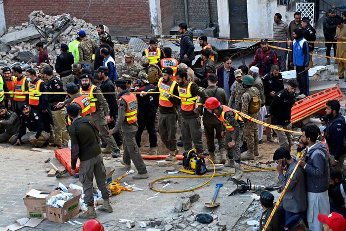 Security officials and rescue workers gather at the site of suicide bombing, in Peshawar (AP Photo)