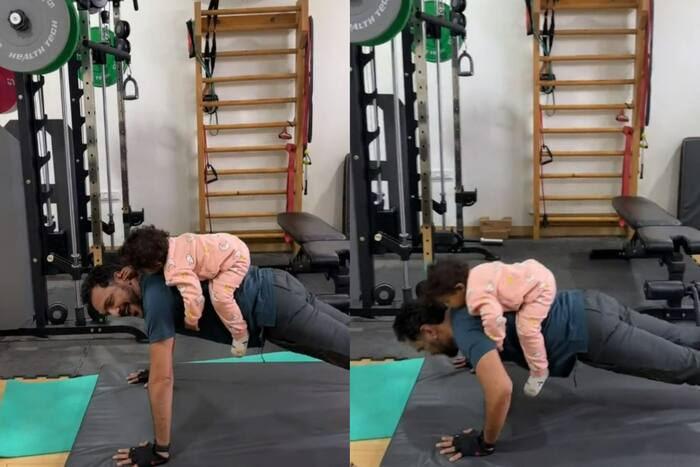 Man does push-ups with baby daughter on his back