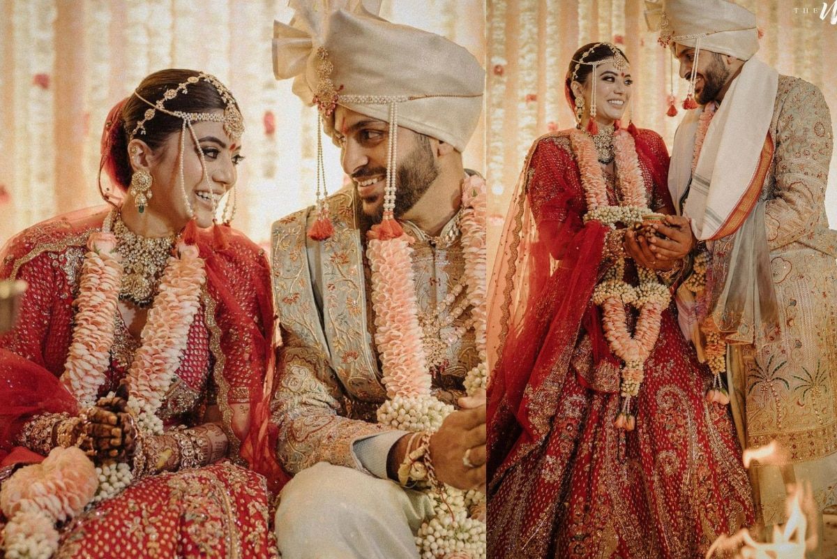 Indian groom dressed in white Sherwani and red hat with stunning bride in red  lehenga stand and hold each hands walking outside Stock Photo | Adobe Stock