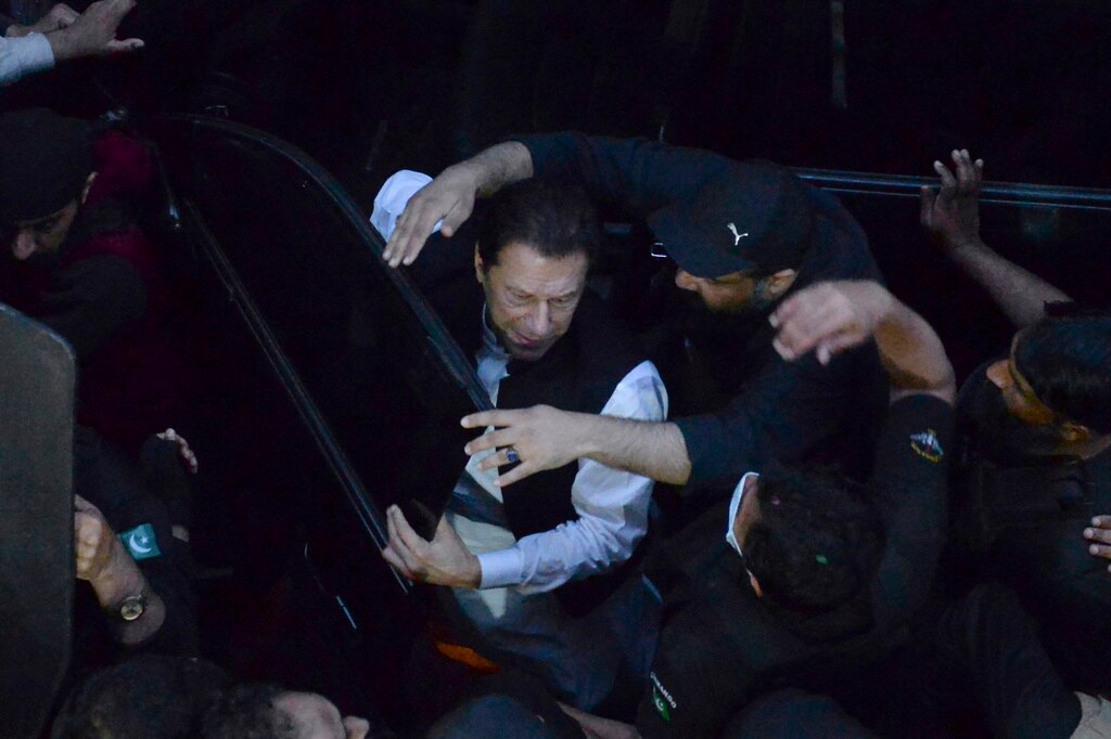 Security personnel make way for former Prime Minister Imran Khan, center, as he arrives to appear in a court (AP Photo)