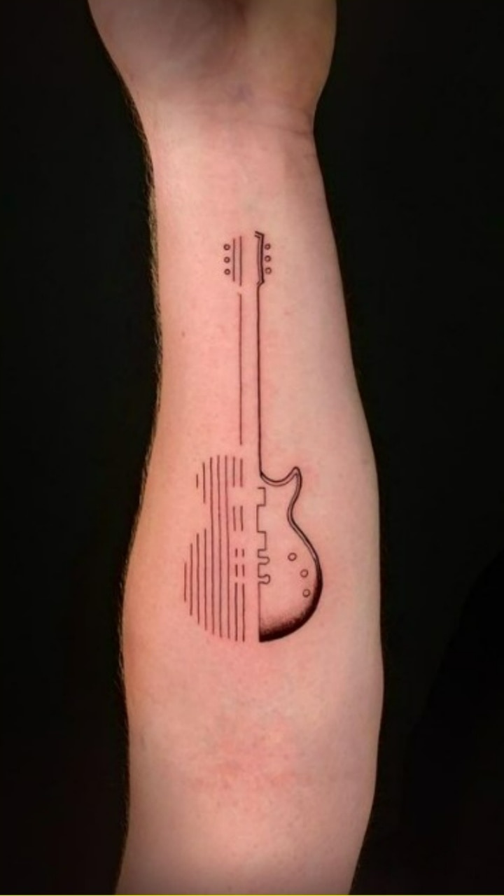 Fine line guitar tattoo on the inner forearm.