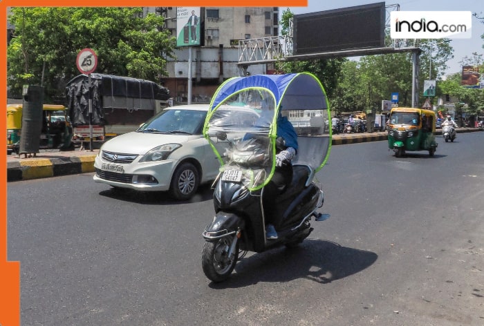 A woman commutes through a two-wheeler placed with a hood used as a cover from heatwave on a hot summer day, in Ahmedabad (PTI)