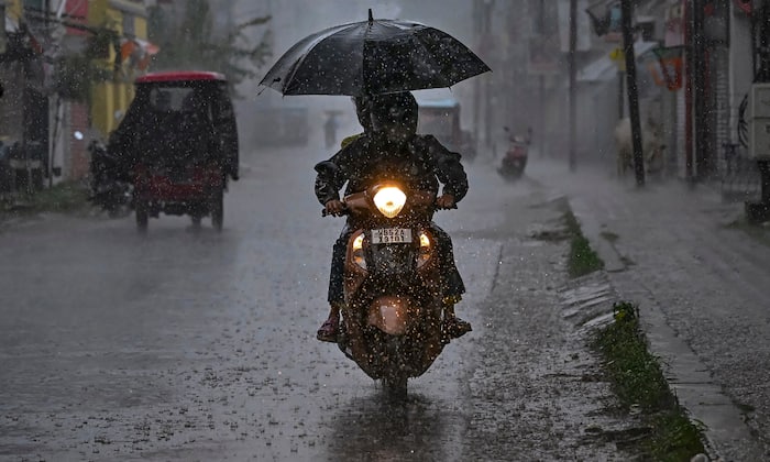 Commuters move on a two-wheeler amid rain (PTI image)