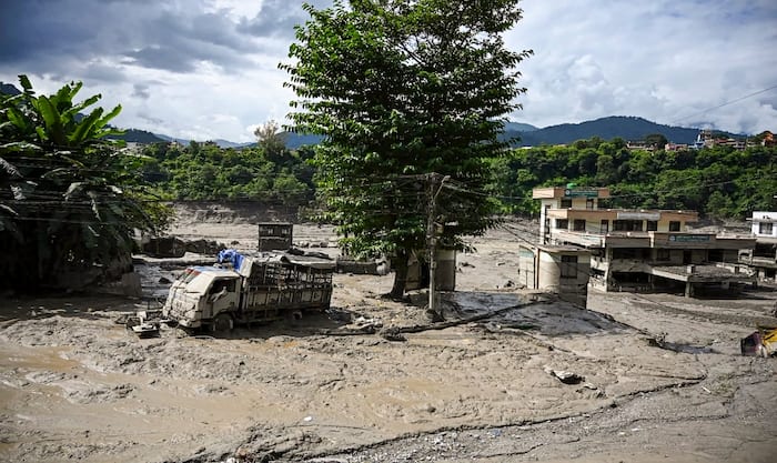 A truck and structures stand partially submerged in a thick layer of mud and debris following flash floods at Beni Ghat area, in Dhading district, Nepal, Wednesday