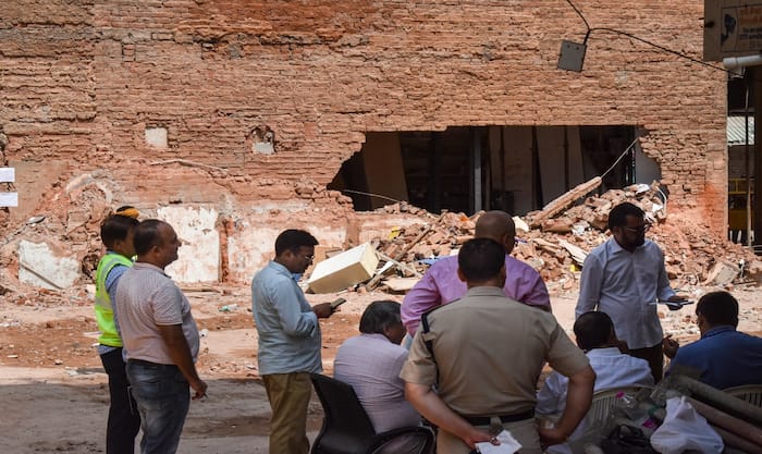 Police officials and people gather at the site during a rescue operation following the collapse of a multi-storey building housing a PG accommodation at Satya Niketan, in New Delhi